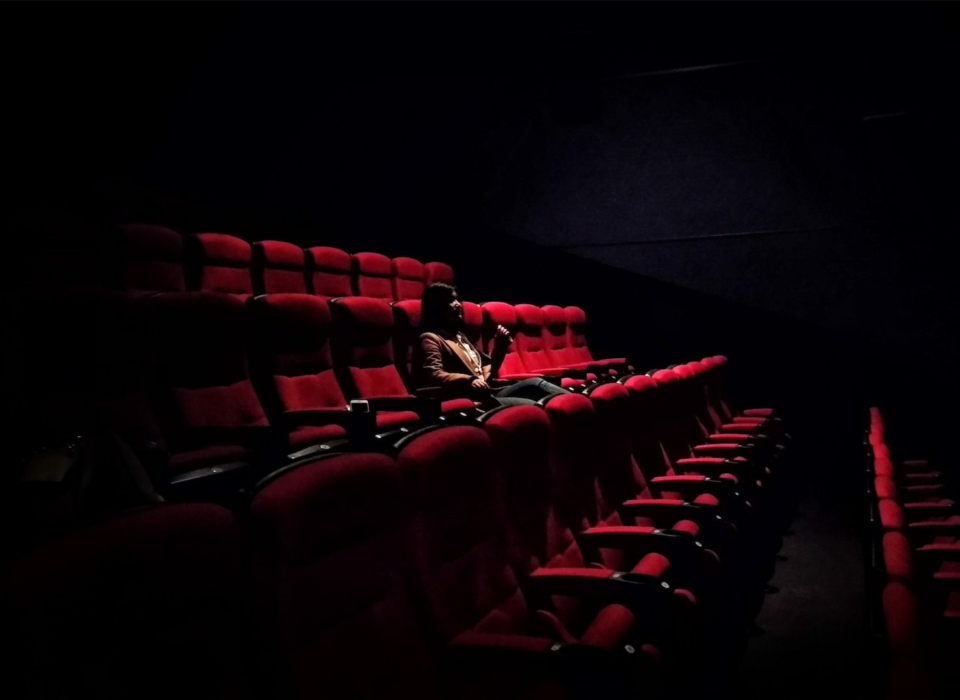 A person sitting in a theater seat in the dark